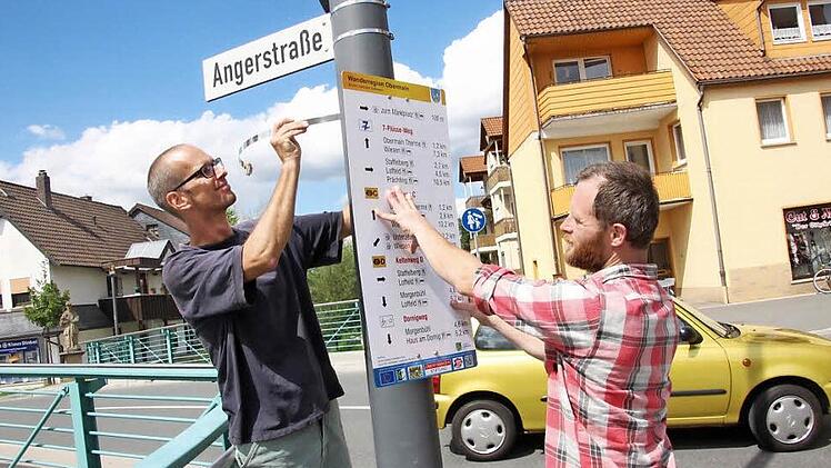 Gunnar Pöhlmann (links) und Matthias Linhart montieren eine der Tafeln für Wanderer an der Brücke zur Angerstraße. Fotos: Tobias Kindermann