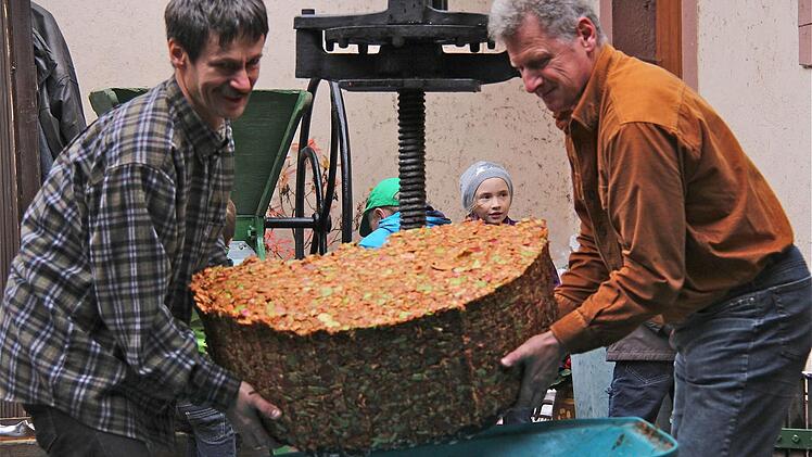 Rainer Schmitt (l.) und Werner Ziegert legen Hand an beim Abtransport des Apfeltresters, den die Schnapsbrenner verwenden .