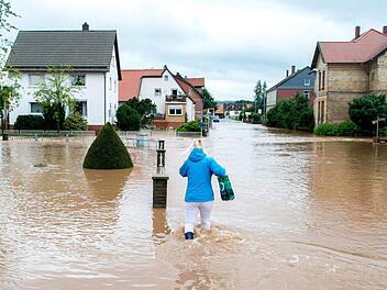 Ein Frau versucht am 26.07.2017 in Rhüden (Niedersachsen), einem Stadtteil von Seesen, durch das hohe Wasser zu gehen. Dauerregen hat im südlichen Niedersachsen in einigen Orten zu Überschwemmungen geführt. Foto: Hauke-Christian Dittrich/dpa