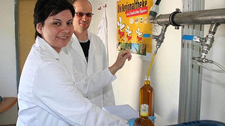 Im  Abfüllraum ziehen Renate und Ralf Geyer das frisch gepresste Öl auf Flaschen.