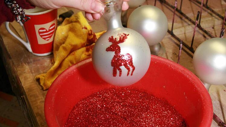 Der Elch bekommt ein rotes Glitzergesicht.