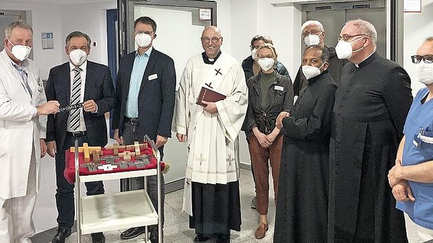 Chefarzt Martin Grauer (l.) und Landrat Alexander Tritthardt (Zweiter v. l.) bringen im Foyer des Kreiskrankenhauses St. Anna die ersten Aufkleber mit dem Neujahrssegen an. Diakon Georg Paszek (Mitte) leitete als Krankenhausseelsorger die Segensfe...
