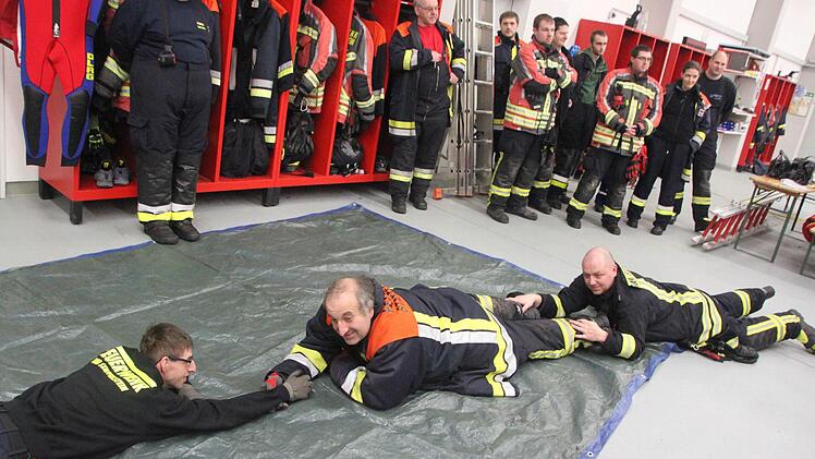 Zunächst üben die Feuerwehrleute in der Fahrzeughalle, dann wenden sie das Erlernte auf der Eisdecke des Riedsees an. Foto: Matthias Einwag