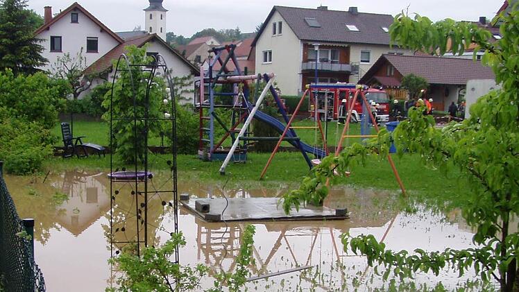 Michael Brehms Garten steht unter Wasser. Im Hintergrund sind Feuerwehrleute dabei, Keller auszupumpen. Foto: privat