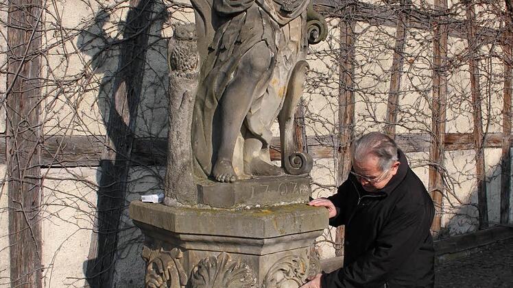 Ingo Hafenecker zeigt die größten Schäden an der Statue im Rathaushof. Foto: Katharina Brecht