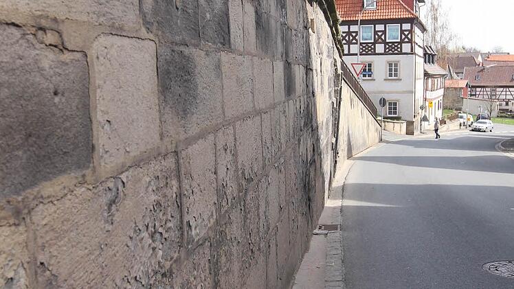 Die Straße geht bis zur Sandsteinwand. Feuchteschäden sind die Folge.