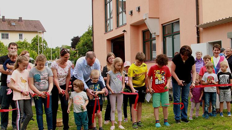 Gemeinsam schnitten Planerin Tanja Potrykus (Vierte von links) und  Bürgermeister Michael Ziegler (Fünfter  von links) sowie Stadtteilsprecherin und Jugendbeauftragte Jutta Aumüller (Fünfte von rechts) mit den Kindern das obligatorische Band durch.