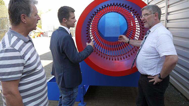 Ein bisschen auffallen darf schon sein: Die kräftigen Farben gehören bei der Brennholz-Reinigungstrommel dazu, erklären Norbert Dressel und Dominic Dressel dem Landrat, Michael Busch, bei der Führung durch das Außengelände des Metallbauspezialisten. Foto: Berthold Köhler