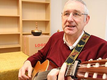 "Gute Nacht Freunde, es ist Zeit für mich zu gehen", spielt und singt Pfarrer Joachim Pennig auf seiner Gitarre. Die ausgeräumten Regale im Hintergrund sind Zeichen der Aufbruchstimmung, die derzeit im Münnerstädter Pfarrhaus herrscht. Foto: Heike Beudert
