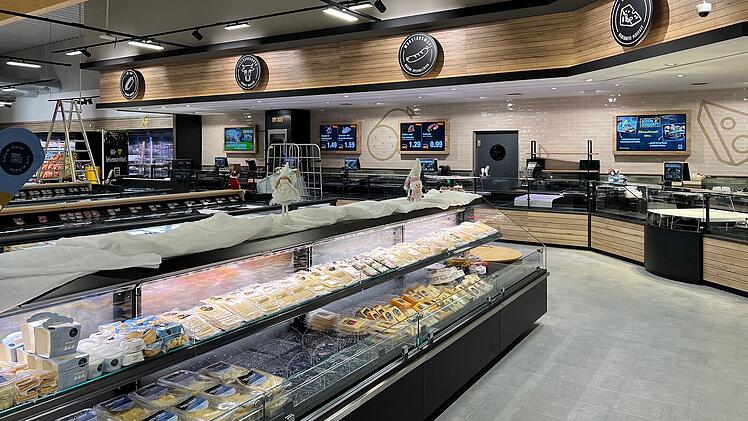 Ein eleganter Edeka-Markt mit Frischtheken und moderner Einrichtung zeigt Lebensmittel in einem einladenden Ambiente. Ein Café-Bereich ist integriert. Alles ist hell und gut organisiert.