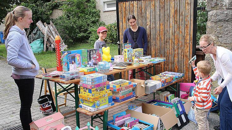 Früh übt sich, was mal ein ausgefuchster Flohmarkthändler werden will. An diesem Stand gab es Spiele, Spielzeug und Kinderbücher und der junge Mann rechts hat auch schon etwas gefunden. Foto: Dieter Britz