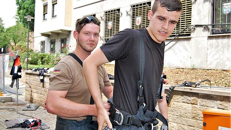 Feuerwehrmann Sascha Rupp (links, FW Hammelburg) half seinem Hammelburger Kameraden Kevin Radler nach dem Vier-Augen-Prinzip beim Anlegen des Auffang- und Sicherungsgurtes mit anhängenden Bandschlingen und Tri-Lock-Karabinerhaken. Sigismund von Dobschütz