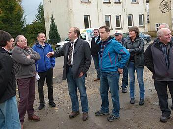 Auch das Haus im Hintergrund wird abgerissen, um im Bahnhofsbereich Parkplätze zu schaffen und um Gewerbe anzusiedeln. Bürgermeister Bernd Reisenweber (Mitte) erläuterte den Gemeinderäten die Vorhaben an dieser Stelle. Foto: Lothar Weidner