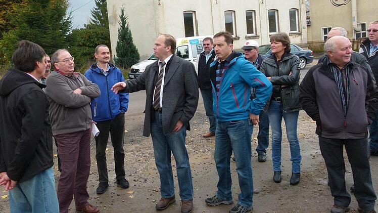 Auch das Haus im Hintergrund wird abgerissen, um im Bahnhofsbereich Parkplätze zu schaffen und um Gewerbe anzusiedeln. Bürgermeister Bernd Reisenweber (Mitte) erläuterte den Gemeinderäten die Vorhaben an dieser Stelle. Foto: Lothar Weidner
