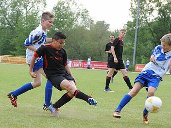 Trotz der Doppelbewachung durch die Auraer Niklas Fella (links) und Mika Manninger kommt Dogukan Sevinc relativ unbedrängt zum Abschluss. Mit dem 3:1-Sieg über den Verfolger bleibt die U-13 der JFG Sinntal/Schondratal II an der Tabellenspitze der Gruppe 1. Foto: Hopf