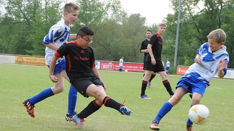 Trotz der Doppelbewachung durch die Auraer Niklas Fella (links) und Mika Manninger kommt Dogukan Sevinc relativ unbedrängt zum Abschluss. Mit dem 3:1-Sieg über den Verfolger bleibt die U-13 der JFG Sinntal/Schondratal II an der Tabellenspitze der Gruppe 1. Foto: Hopf