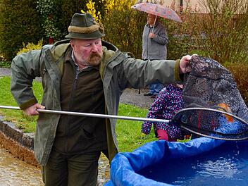 Werner Kirchner hat beim Fischfang kräftig unterstützt. Hier lässt er einen Goldfisch in das extra für die Tiere bereitgestellte Faltbecken plumpsen. Im Hintergrund ist Hiltrud Metz zu sehen, die Frau des verstorbenen Helmut Metz. Foto: Kathrin Kupka-Hahn