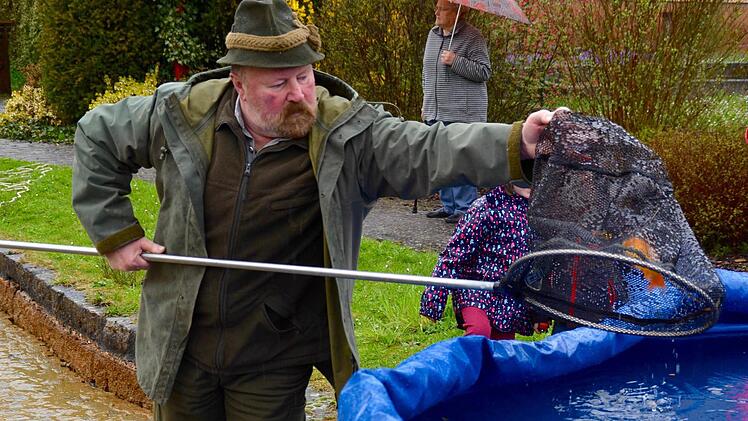 Werner Kirchner hat beim Fischfang kräftig unterstützt. Hier lässt er einen Goldfisch in das extra für die Tiere bereitgestellte Faltbecken plumpsen. Im Hintergrund ist Hiltrud Metz zu sehen, die Frau des verstorbenen Helmut Metz. Foto: Kathrin Kupka-Hahn