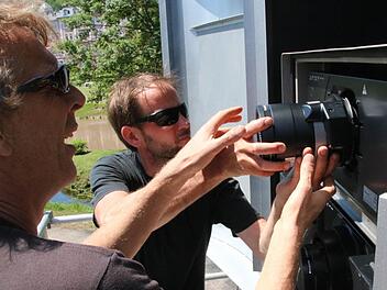Olaf Kasprzyk (von links) und Claus Rau montieren die Objektive der beiden Beamer im hochwassersicheren und klimatisierten Gehäuse. Foto: Ralf Ruppert