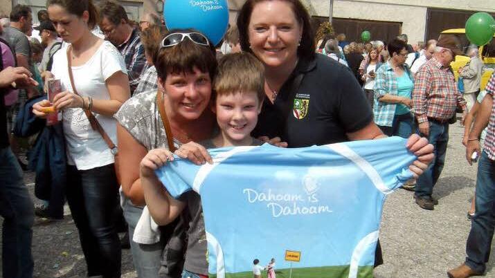 Luca Ströhlein präsentiert sein neues "Dahoam is Dahoam"-Shirt zusammen mit Mutter Kerstin (links) und Kerstin May. Foto: Susanne Deuerling