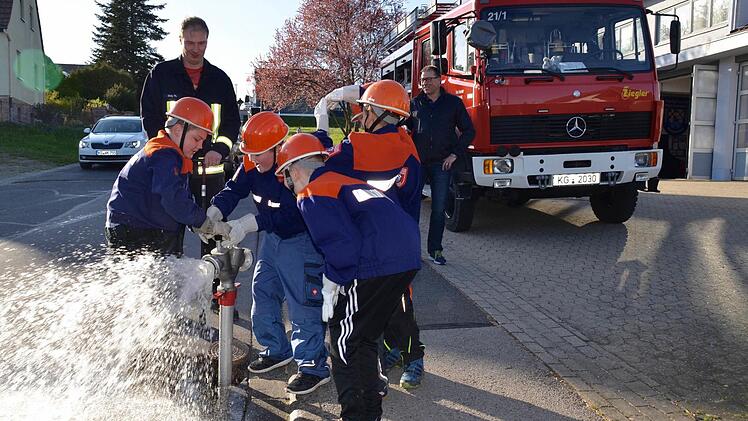 Linus (rechts) und Leon sind nun dabei, das Ventil am Standrohr wieder zu schließen. Kommandant Thomas Geis (links) schaut, ob sie es richtigmachen, ebenso Erwin Below (rechts). Foto: Kathrin Kupka-Hahn