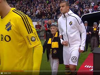 Die Spieler des AIK Solna laufen im Spiel gegen Gefle IF mit Senioren auf Spielfeld. Foto: Screenshot, YouTube AIK play