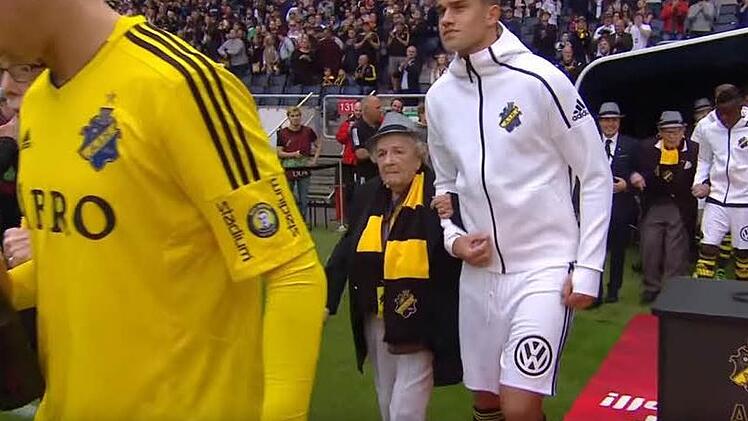Die Spieler des AIK Solna laufen im Spiel gegen Gefle IF mit Senioren auf Spielfeld. Foto: Screenshot, YouTube AIK play