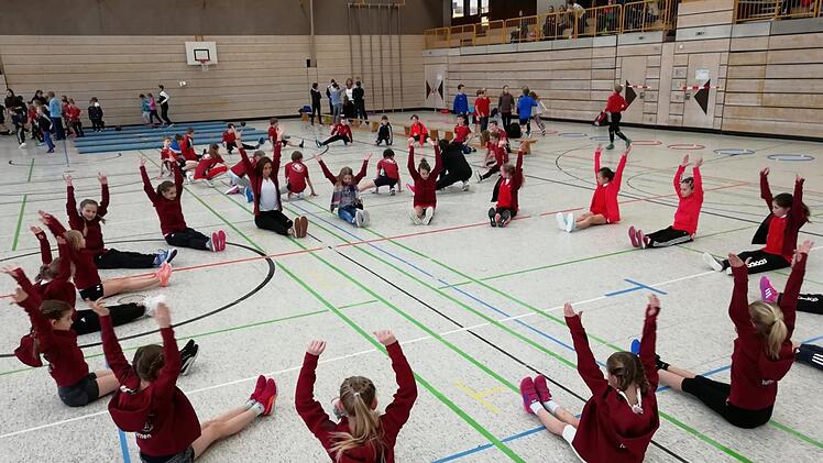 Während sich Miriam Müller (weißes T-Shirt) mit den Turnerinnen aufwärmt, macht Steffi Santjer (schwarzer Anzug) mit den Leichtathleten Übungen. Fotos: Peter Müller