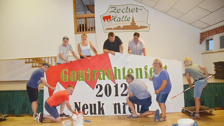 Mitglieder des Festausschusses sind derzeit mit vielerlei Vorbereitungsarbeiten beschäftigt. Dazu gehört auch die Herstellung großer Einladungsbanner für das Gautrachtenfest am Sonntag, 9. September. Da wird gemalt, gebohrt und gehämmert. Mit im Bild Vorsitzende Bettina Rubel  (oben Zweite von links)Karl-Heinz Hofmann