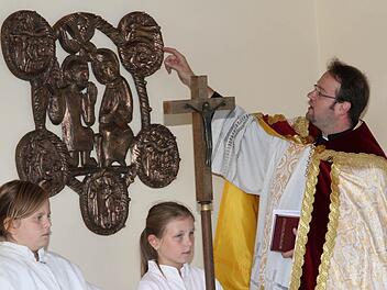 Pfarrer Daniel Schuster erklärt die Darstellungen auf dem Bronzerelief, das an der Drosendorfer Aussegnungshalle einen neuen Standort gefunden hat.  Foto: Erlwein