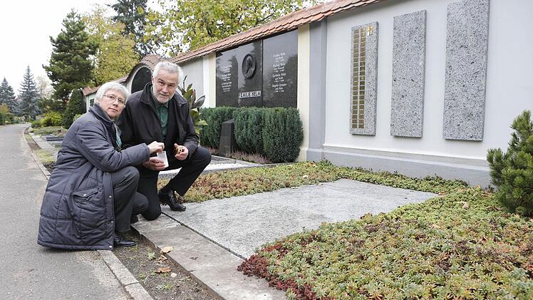 Anne Bergen und Michael Maisch vom Hospizverein Bamberg entzünden ein Licht an der Grabanlage, in der Menschen beigesetzt werden, die einsam und meist mittellos gestorben sind. Foto: Matthias Hoch