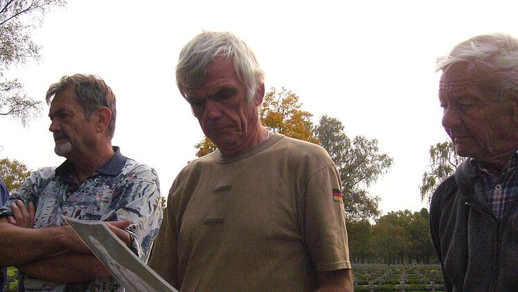 Günter Behr, Benno Trost und Wilfried König studieren bei der Friedhofsführung alte Bilder. Foto: Paul Ziegler