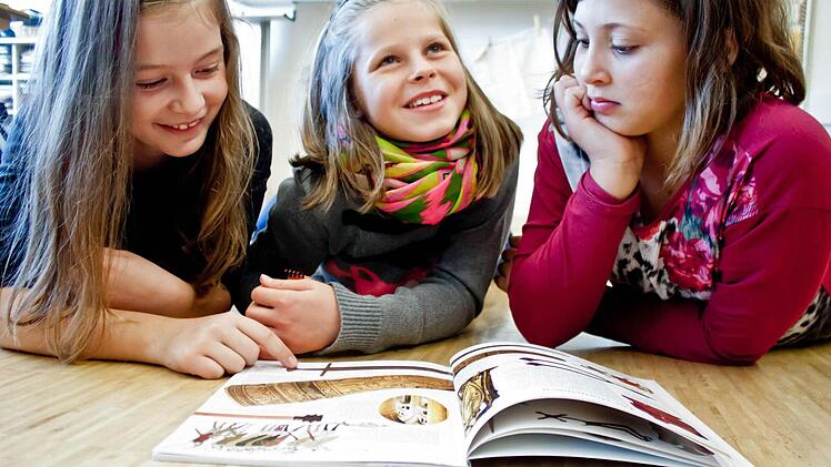 Lena, Alina und Melanie (von links) informieren sich in einem Buch über das Mittelalter. Foto: Jochen Berger