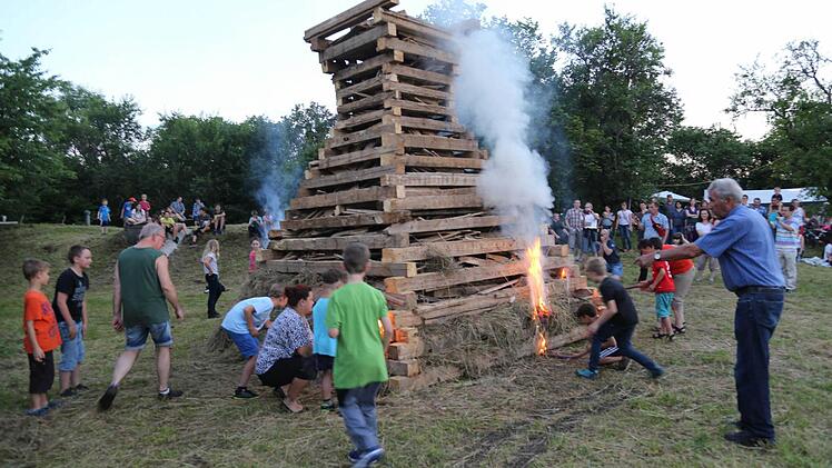 Die Kinder dürfen mit Fackeln den Holzstoß entzünden. Foto: Franz Galster