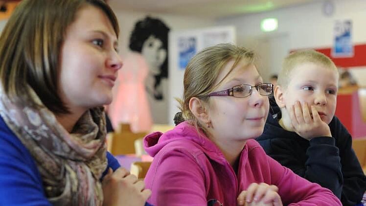 Erzieherin Elena Lebold, Nicole und Maik Schulteis (von links) lassen sich von Franz Scholles die Regeln zu einem Gemeinschaftsspiel erklären.