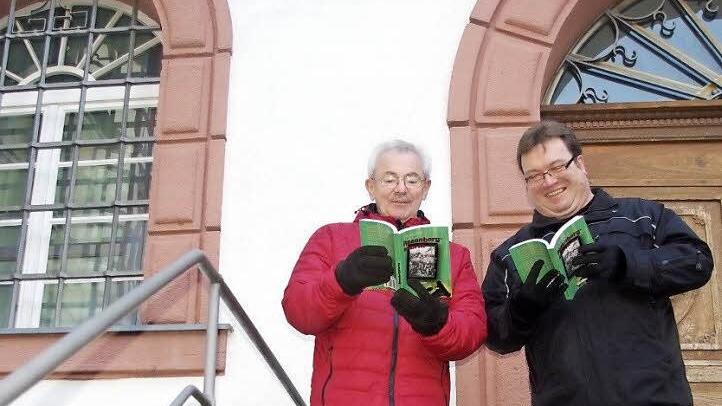 Manfred Raum und Udo Georg Gellner schmökern auf der Treppe zur historischen Markthalle im ersten Kronacher Thriller "Rosenbergsturm".  Foto: Heike Schülein