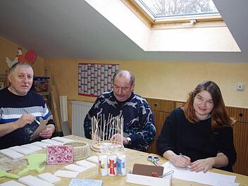 Die Bewohner im Haus Fischbachtal laden zum Osterbasar ein. Peter (links) bemalt Holz-Osterhasen, Siegfried ist mit der Herstellung eines Osterkörbchens beschäftigt und Claudia fertigt in Linolschnitt schöne Karten an.  Foto: Karl-Heinz Hofmann