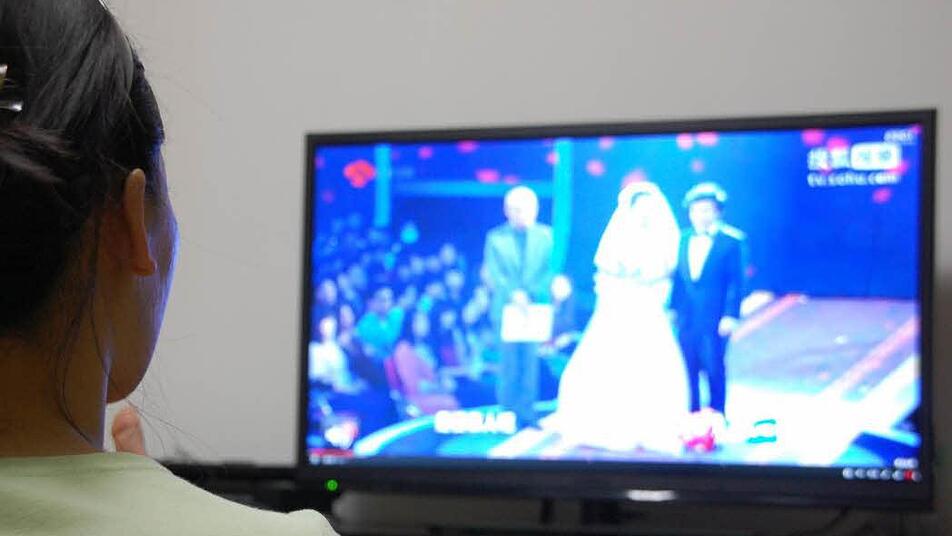 Eine junge Chinesin schaut die Sendung «Fei Cheng Wu Rao» im Fernsehen. Jede Woche fesselt die Speed-Dating-Show Millionen Chinesen vor den Fernsehern. Foto: dpa