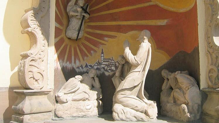 Die Ölberggruppe rechts neben dem Eingang zeigt barocke Steinfiguren, die aus der Zeit vor dem Brand der Kirche 1903 stammen.