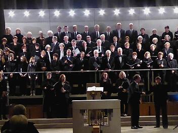 Alle drei Chöre präsentieren sich auf dem riesigen Chorgerüst hinter dem Altar der Herz-Jesu-Kirche mit ihrem Leiter Burkard Ascherl, Brigitte Ascherl (links) und ihrer musikalischen Unterstützung auf dem elektrischen Klavier, Ute Stibor (rechts) beim Schlussapplaus. Foto: Gerhild Ahnert