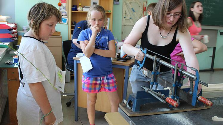 Eine Kette mit einem Holzkreuz konnte man bei den Kirchlauterer Ministranten basteln. Oberministrantin Johanna Borschert half tatkr&auml;ftig beim S&auml;gen mit. Fotos: Baumg&auml;rtner