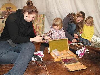 Im Inneren des Tipis ist es angenehm trocken und warm: Michaela Gabor, Lucie hoch (4), Sarah Milz und Sophie Milz (3) basteln Schmuck aus Specksteinen. Foto: Sonja Adam