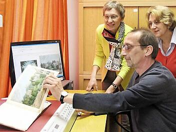 Peter Fenzel beim Digitalisieren des "Souvenir de Cobourg", einem Band mit aquarellierten Ansichten aus Coburg. Bibliotheksleiterin Silvia Pfister und Renate Bauer (von links) schauen über die Schulter.