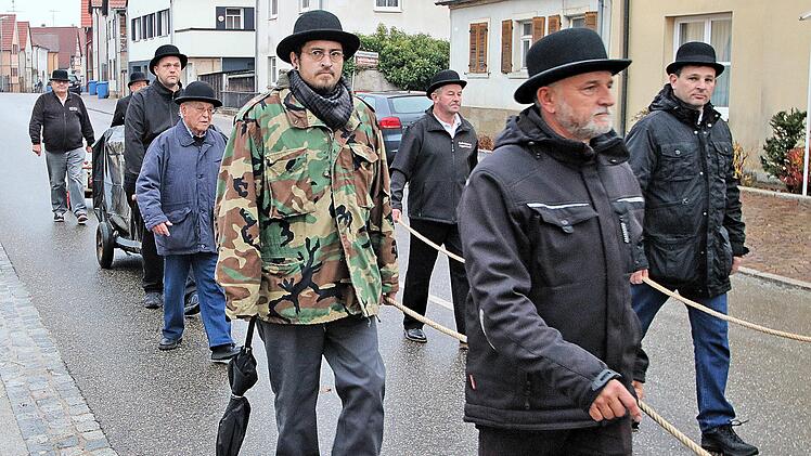 Ohne ein Schwein zogen die Mitglieder der Cocks-Innung am Dienstagmorgen  durch Poppenlauer. Der leere Schweinekäfig war mit einer schwarzen Plane  bedeckt und erinnerte entfernt an einen Sarg. Foto: Dieter Britz