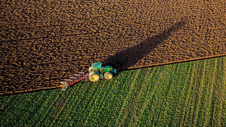Ein Traktor pflügt in der Abendsonne einen Acker eines Biohofes bei Medewege in der Nähe von Schwerin (Aufnahme mit einer Drohne). Landwirte beklagen sich aktuell über zu langsames Internet und schlechten Mobilfunkausbau auf dem Land. Sie fordern mehr Anstrengung von der Bundesregierung. Symbolfoto: Jens Büttner/dpa-Zentralbild/dpa