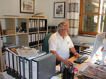 Peter Hänel in seinem Arbeitszimmer in seinem schmucken Eigenheim am Allerswald. Vorne links die Akten zur Finanzierung des Bildungszentrums. Hinten an bzw. vor der Wand (von links): ein Bild des Marktplatzes der englischen Partnerstadt Bingham, ein Floßhaken der Flößergemeinschaft Wallenfels und eine Urkunde der Soldatenkameradschaft.  Foto: Friedwald Schedel