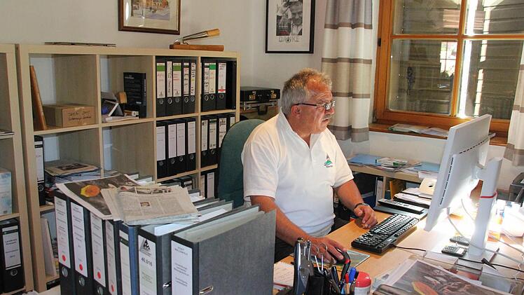 Peter Hänel in seinem Arbeitszimmer in seinem schmucken Eigenheim am Allerswald. Vorne links die Akten zur Finanzierung des Bildungszentrums. Hinten an bzw. vor der Wand (von links): ein Bild des Marktplatzes der englischen Partnerstadt Bingham, ein Floßhaken der Flößergemeinschaft Wallenfels und eine Urkunde der Soldatenkameradschaft.  Foto: Friedwald Schedel