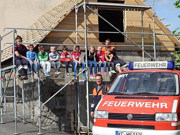 Die Jungen und Mädchen der Kinderfeuerwehr und ihre Betreuer Bianca Schönmüller (links oben), Harry Neder (rechts oben) sowie Alexander Hoderlein (vorne) - zugleich Vorsitzender der FFW Hesselbach - freuen sich, dass das neue Fahrzeug eine schöne Unterstellmöglichkeit erhält.