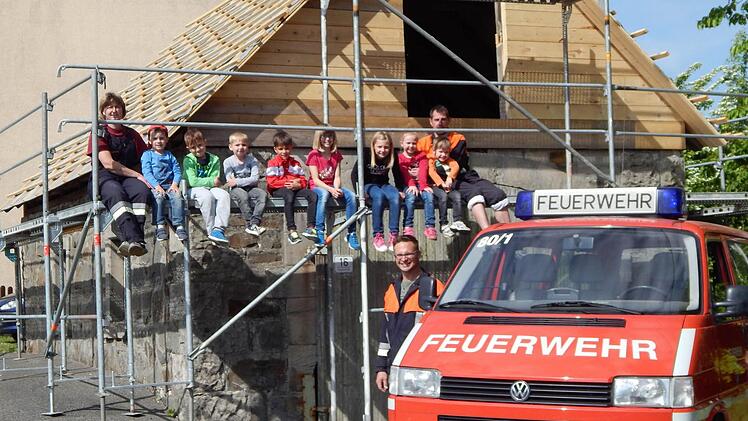 Die Jungen und Mädchen der Kinderfeuerwehr und ihre Betreuer Bianca Schönmüller (links oben), Harry Neder (rechts oben) sowie Alexander Hoderlein (vorne) - zugleich Vorsitzender der FFW Hesselbach - freuen sich, dass das neue Fahrzeug eine schöne Unterstellmöglichkeit erhält.