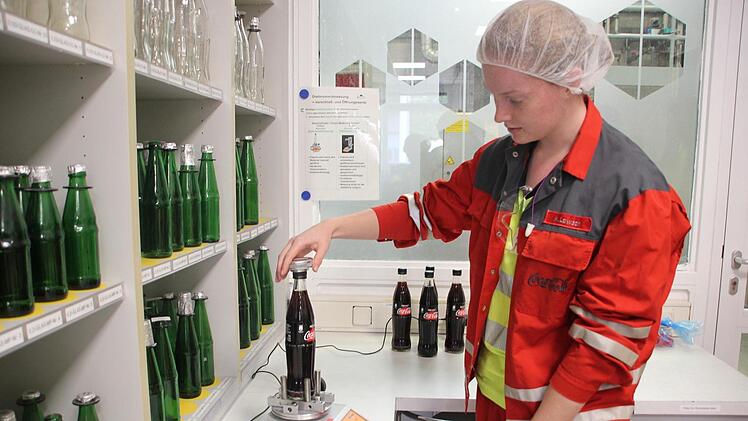 Michelle Lawson zeigt das alte Verfahren: Flasche händisch aufdrehen und Kraftaufwand messen. Heute dreht eine Maschine die Flasche auf (immer gleiche Kraft).
